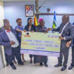 UEDCL Managing Director Paul Mwesigwa (second-right) hands over a dummy cheque for UGX. 5 million to the Bishop of Hoima Catholic Diocese, Rt. Rev. Vincent Kirabo Amooti (sixth-left) and other UEDCL officials on Friday 8th August 2025 at UEDCL Tower.